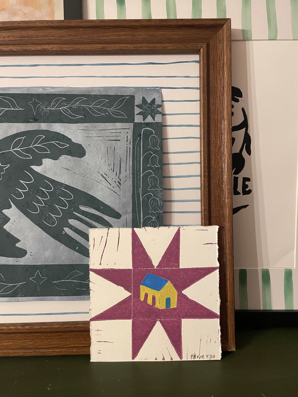 Framed folk art quilt artwork with abstract designs on a wall