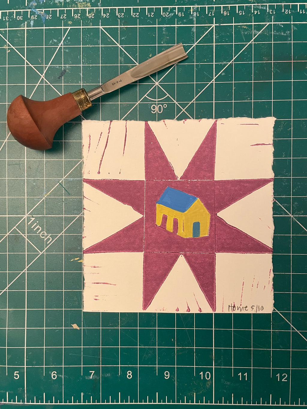 Fabric square with star and hand design on a green cutting mat with ruler